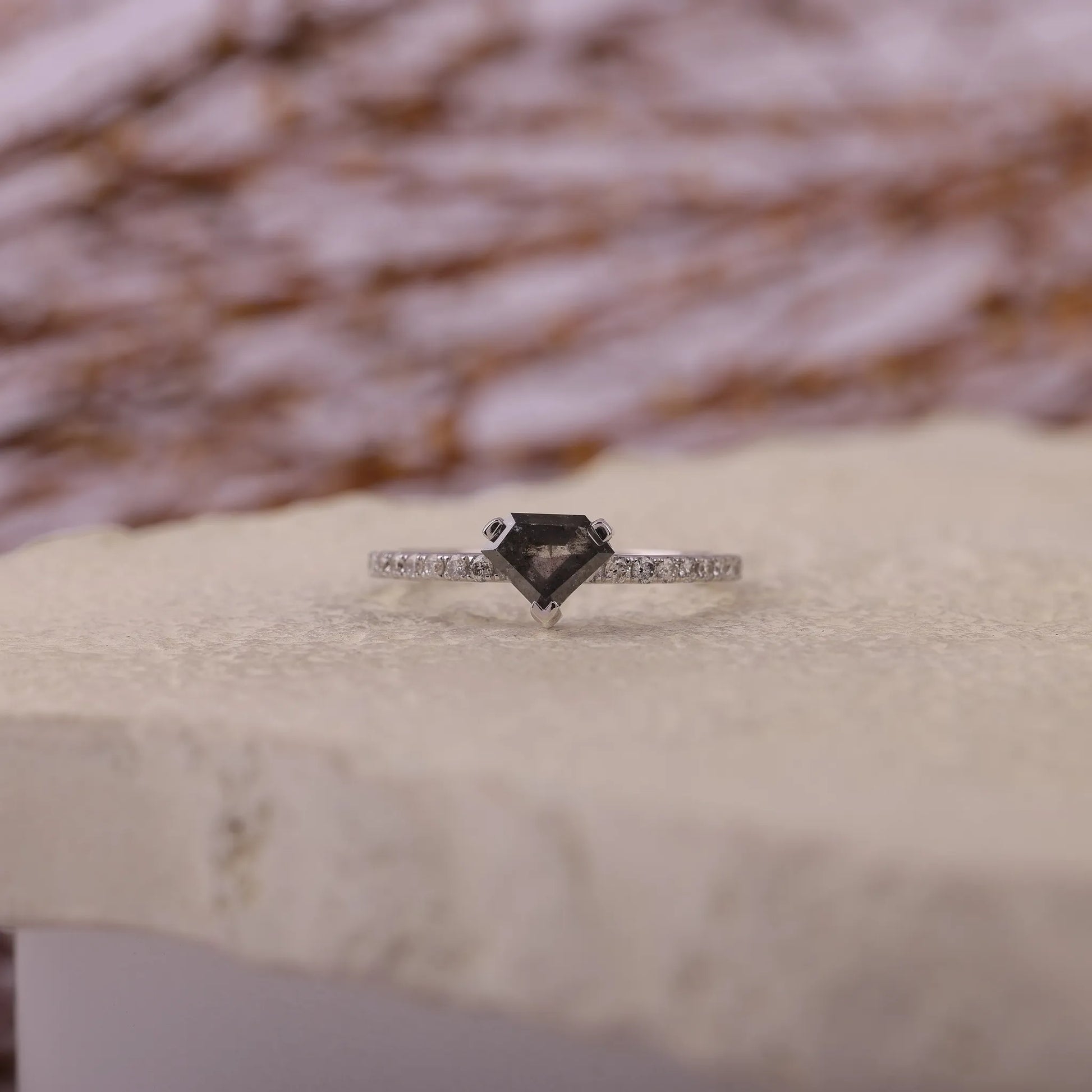 Ring with a black diamond and smaller diamonds on a textured surface