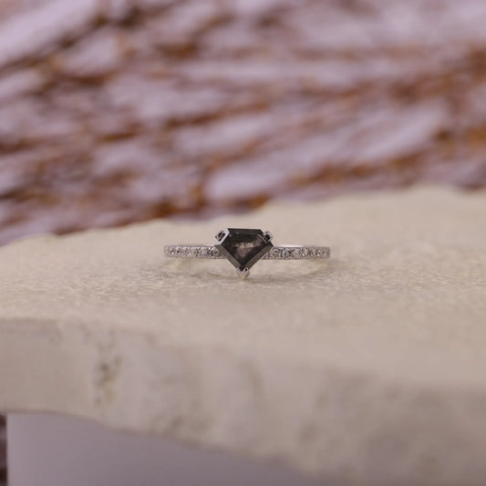 Ring with a black diamond and smaller diamonds on a textured surface
